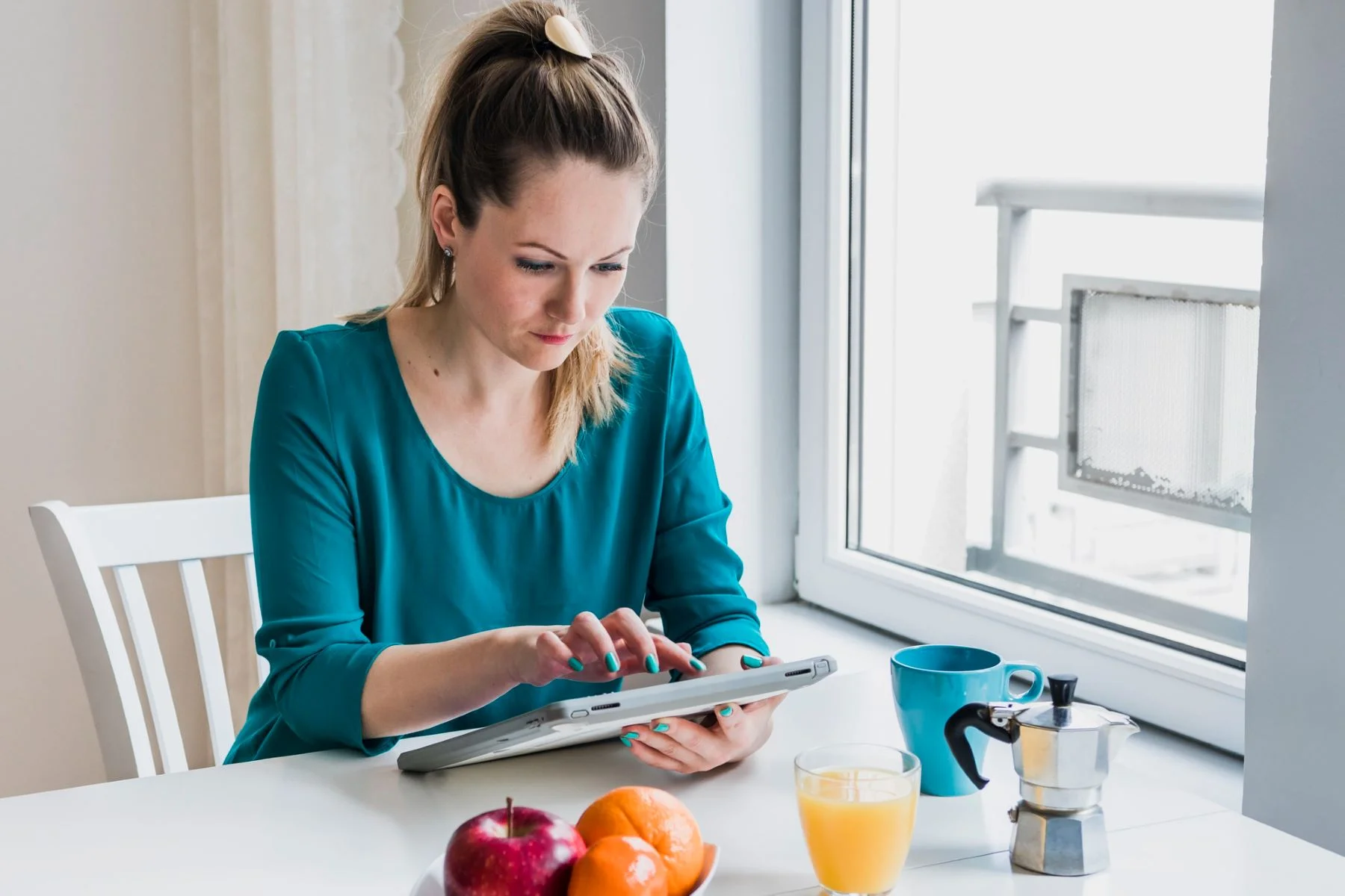 Woman browsing tablet during breakfast