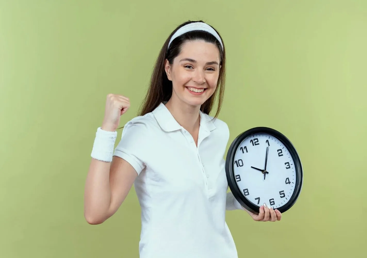 Young fitness woman in headband holding wall clock