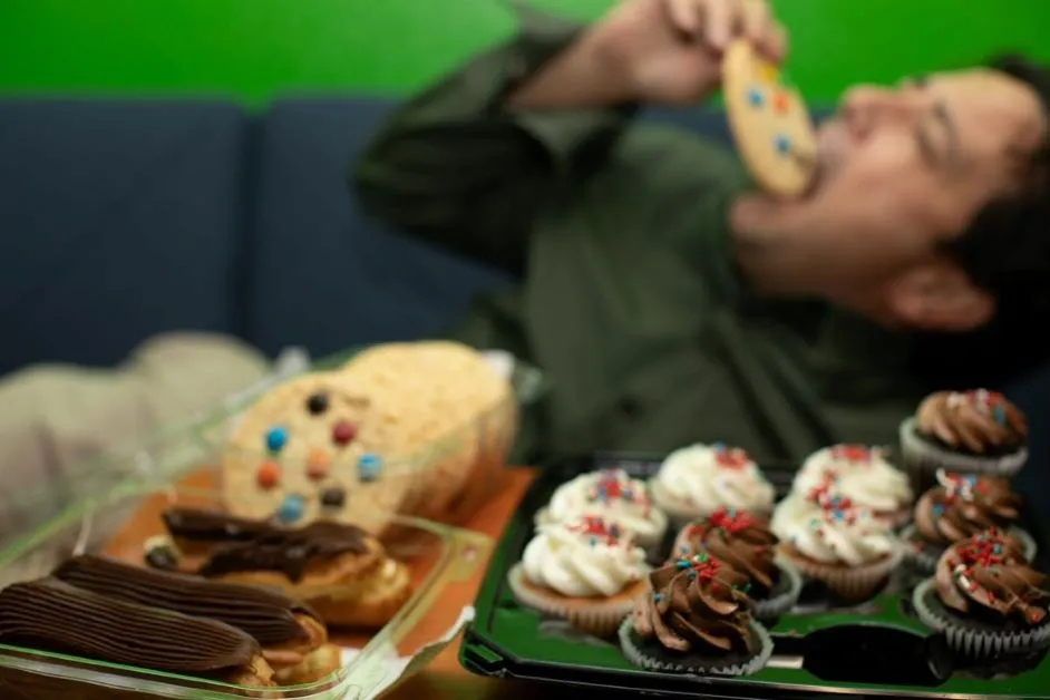 some bakery food on the table and a young boy lying on sofa