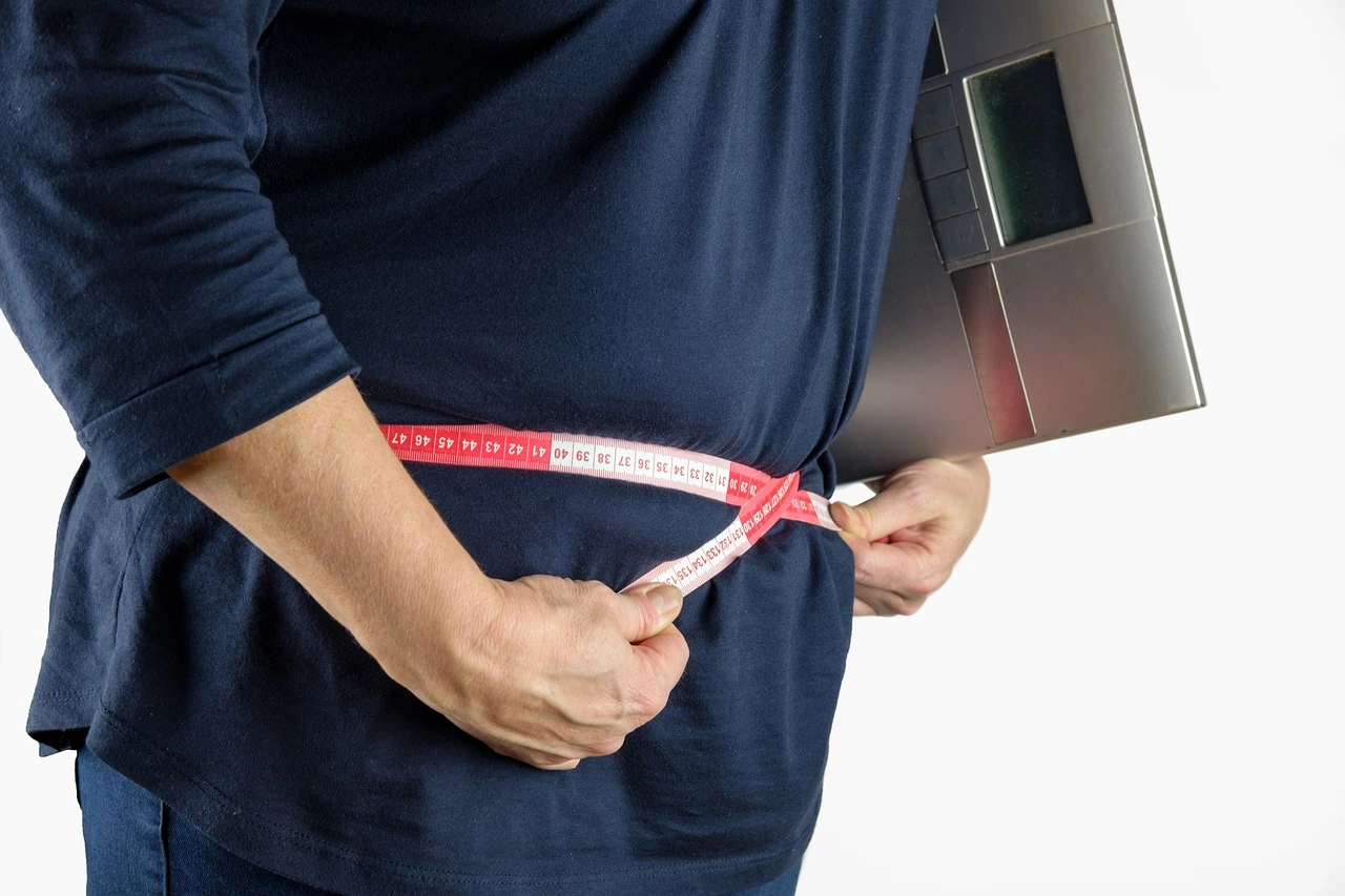 A man measuring his waist with measure tap