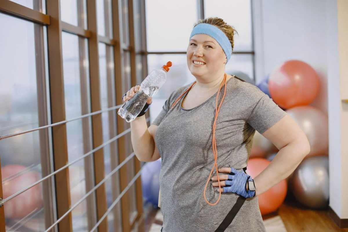 Fat woman dieting, fitness. Lady with rope. Woman in gray sports suit.